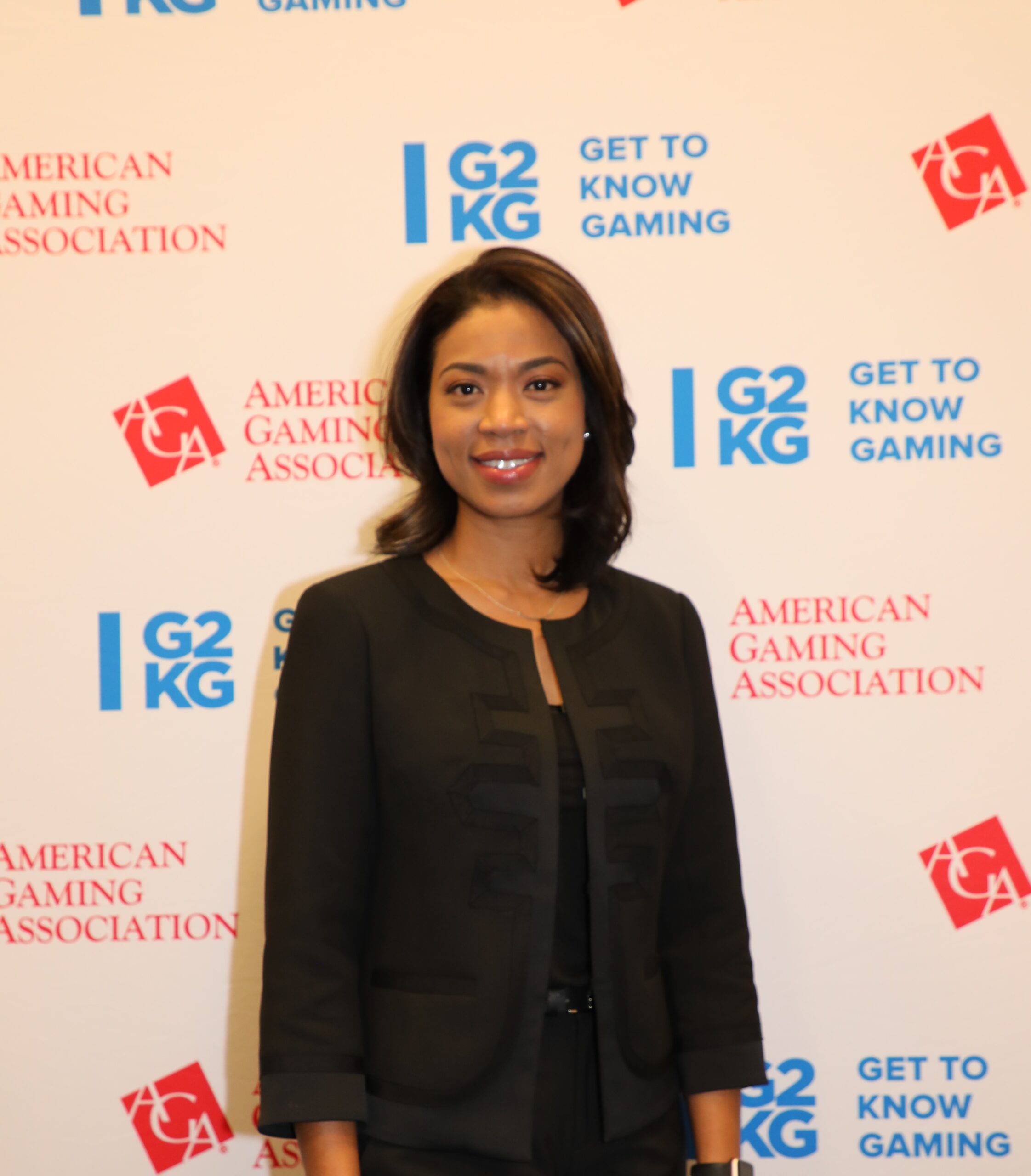 A person in a black outfit is smiling in front of a backdrop that reads "American Gaming Association" and "Get to Know Gaming" with logos.