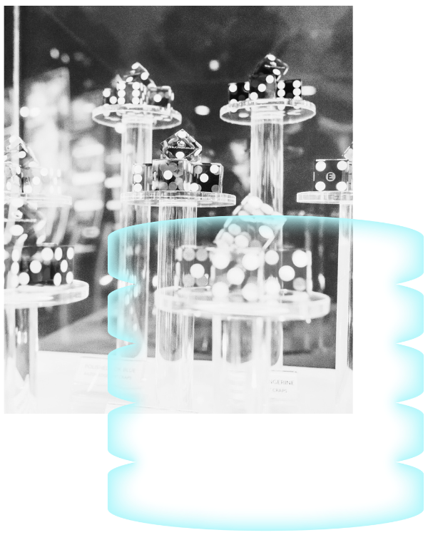 Black and white photo of large dice displayed on clear cylindrical stands, with a bright blue abstract shape partially overlaid at the bottom edge of the image.